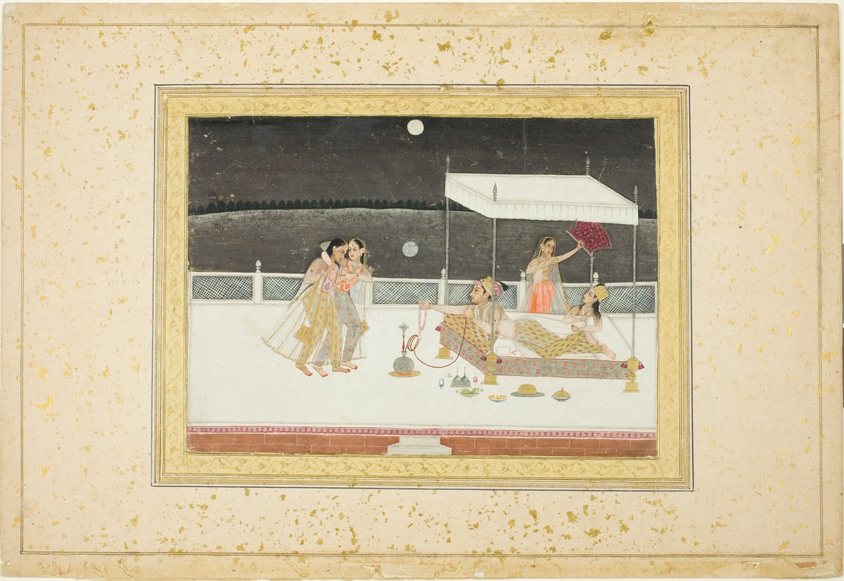 Miniature painting in a gold-flecked border: on a white palace terrace under a night sky and full moon, a man and a woman recline on a bed beneath a canopy while an attendant waves a fan, and two women embrace at left.