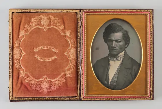 Historical black and white photographical portrait of Black man in a suit, gold frame.