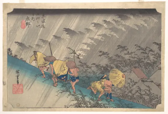 Woodblock print of travellers caught in a sudden downpour on a steep road: porters carrying a palanquin and men in straw rain capes and hats hurry in opposite directions, bent against slanting grey rain, past bamboo whipped by the wind.