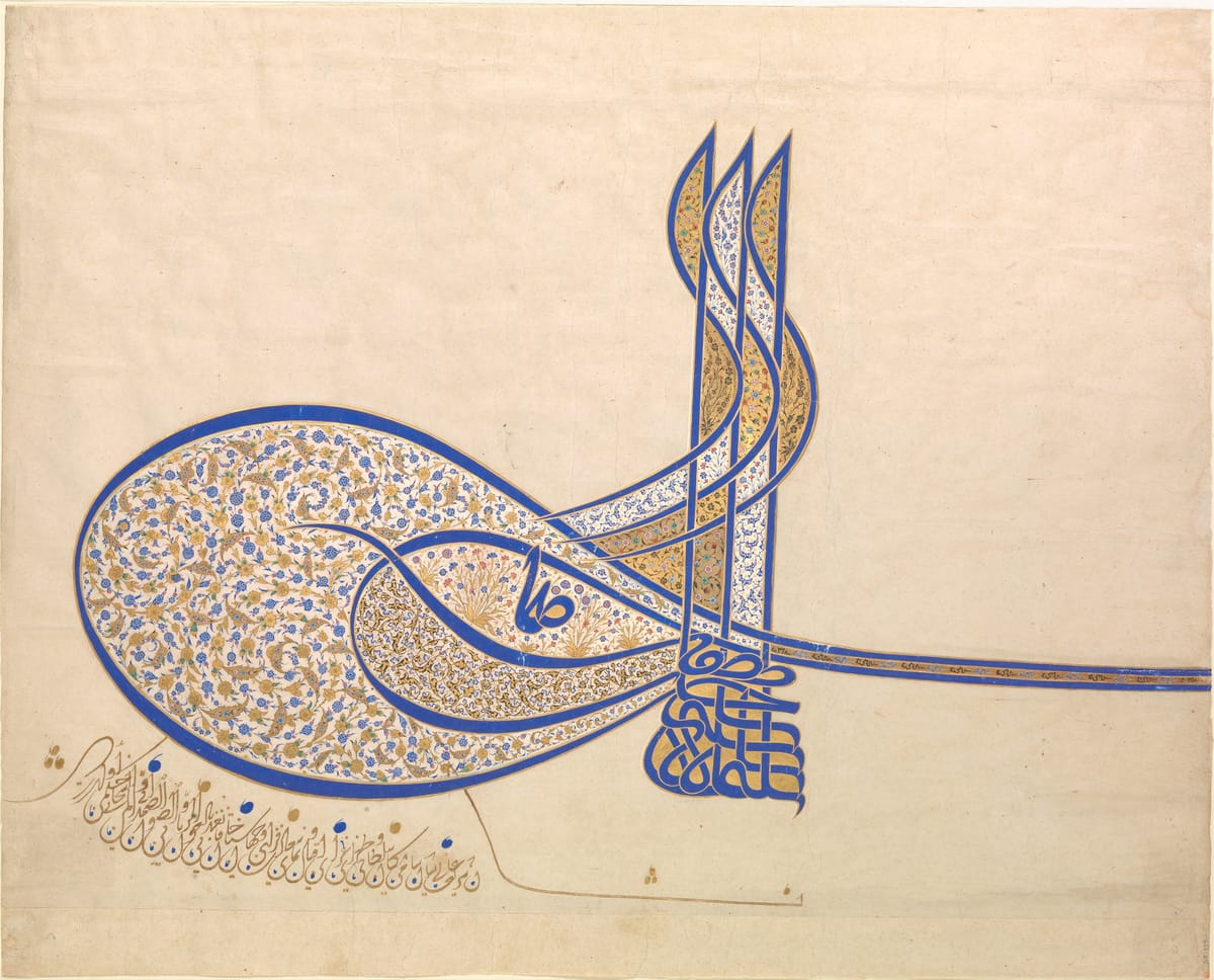 The sultan’s calligraphic monogram in blue ink and gold on cream paper: three tall vertical strokes rise from a base of interlaced letters, with a large oval loop to the left and long strokes sweeping off to the right, all filled with fine blue and gold floral scrolls.