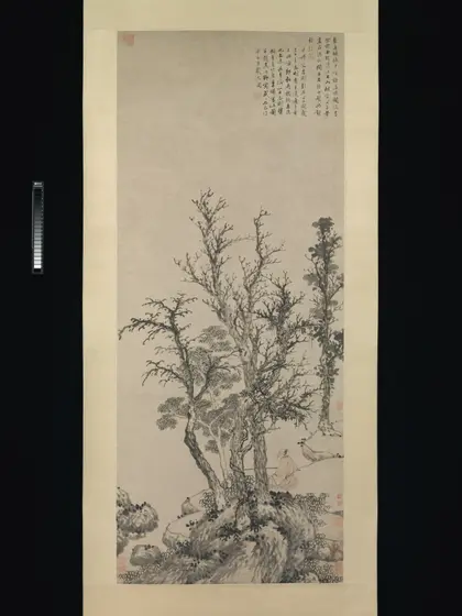 Tall hanging scroll in ink and light colour on paper: a cluster of bare and sparsely leaved trees rises from rocks along a bank, with a few columns of handwritten inscription at the upper right.