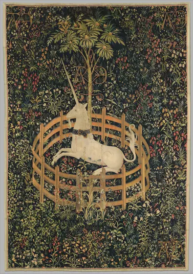 Tapestry of a white unicorn with a gold collar lying inside a low, round wooden fence, chained to a fruit-laden pomegranate tree, against a dense dark-green ground filled with flowers and plants.